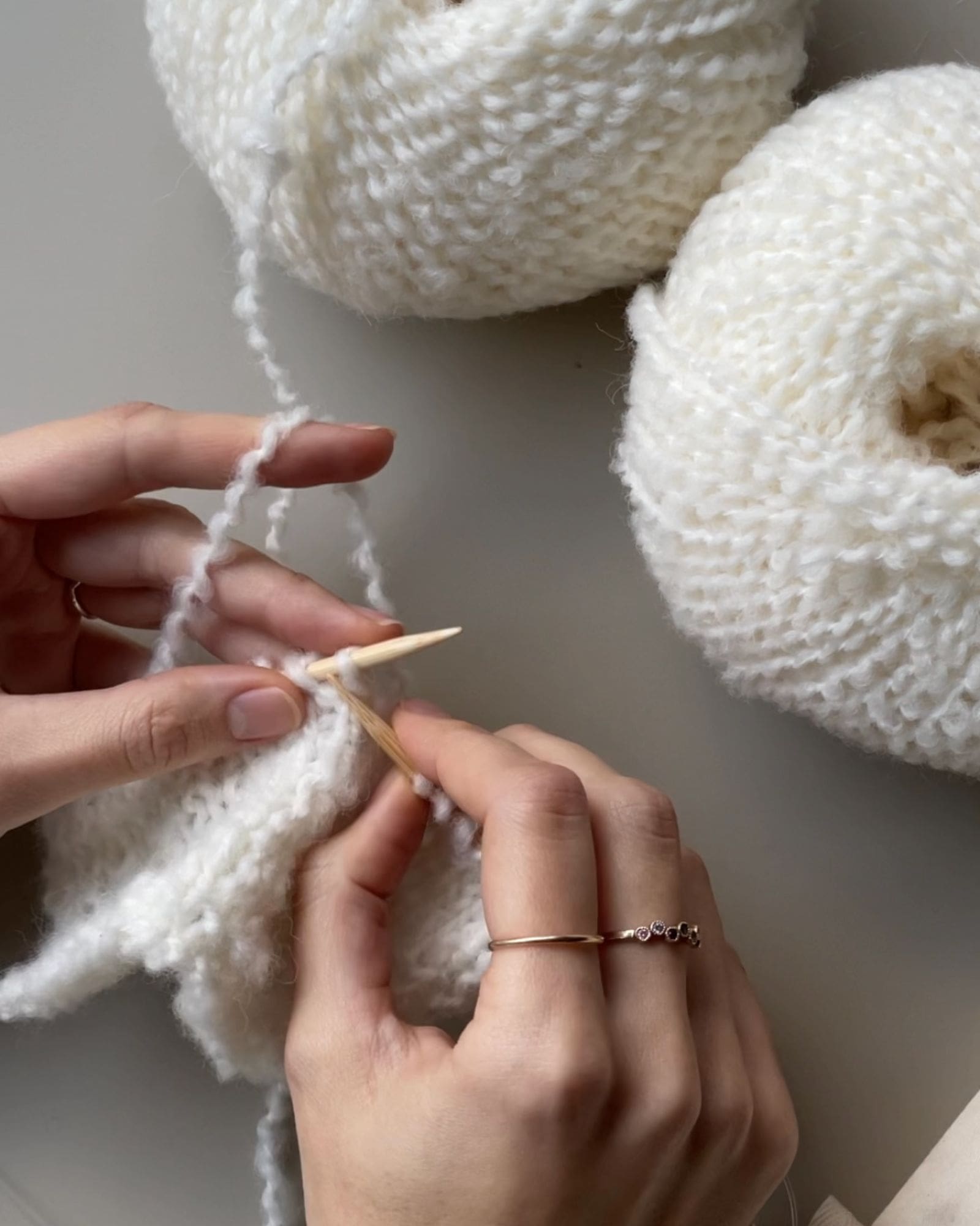 En person er ved at strikke noget i den hvide Buclé-garn m. Seeknits udskiftelige pinde.