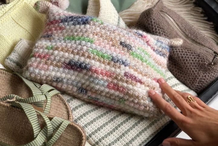 En person har pakket en kuffert til sin sommerferie. Forrest ligger en Shell clutch med strikkepinde osv. til rejsen.