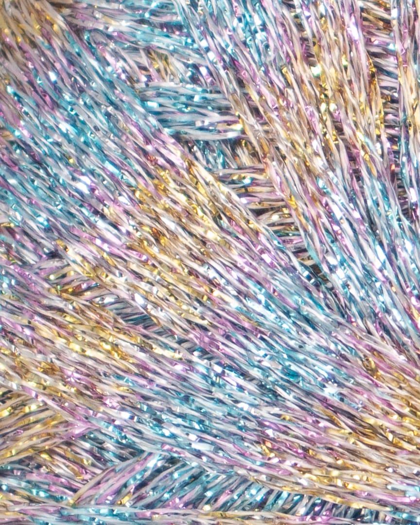 Paia Glimmergarn i fv. 713 Unicorn Shimmer, der er en sart farvekombination af lyseblå, guld og lilla.