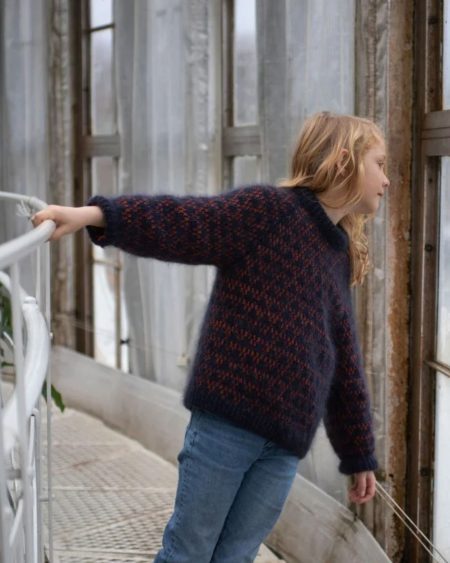 Barn iført Anne Ventzels Spot Junior i mørkeblå med orange mønster.