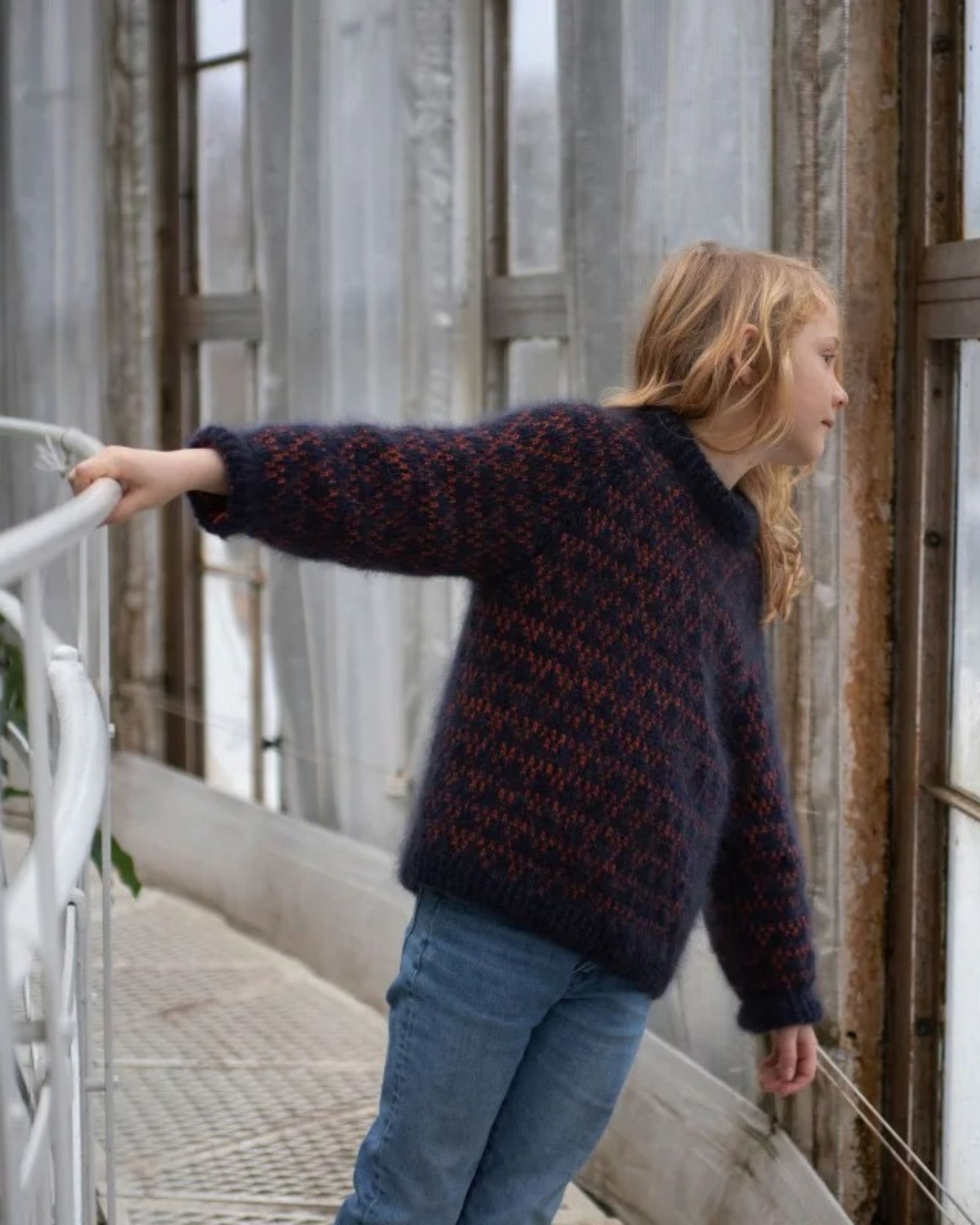 Barn iført Anne Ventzels Spot Junior i mørkeblå med orange mønster.