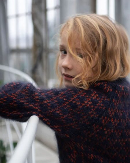 Nærbillede af barn iført Anne Ventzels Spot Junior i mørkeblå med orange mønster.